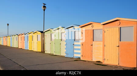 Une rangée de vingt des cabanes de plage la plus proche est la plus grande la ligne a une diminution de la perspective qu'ils sont de couleur orange, vert yell Banque D'Images