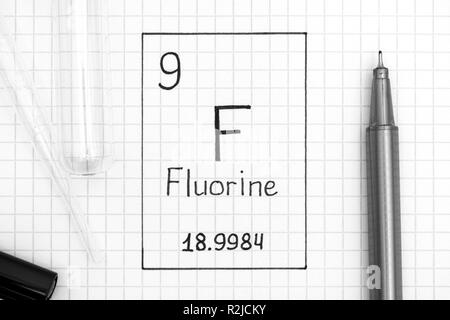 Le tableau périodique des éléments. L'élément chimique fluor F L'écriture avec un stylo noir, tube à essai et pipette. Close-up. Banque D'Images