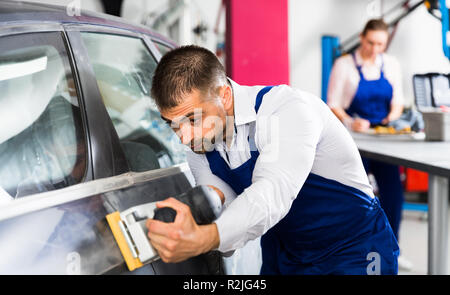 L'accent mécanicien de voiture en atelier de carrosserie ponçage, préparation pour la peinture Banque D'Images