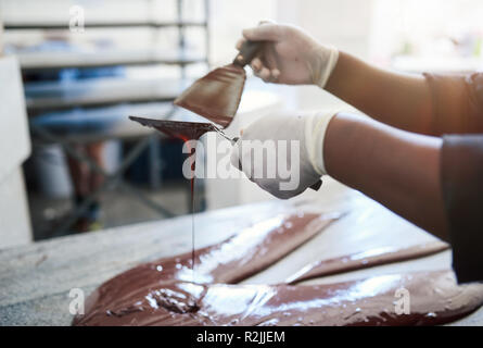 Mélange de chocolat artisanal travailleur avec spatules sur une table Banque D'Images