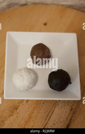 Délicieux blanc, le lait et le chocolat noir boules sur table en bois Banque D'Images