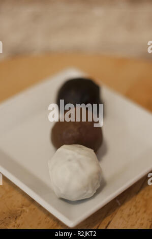 Délicieux blanc, le lait et le chocolat noir boules sur table en bois Banque D'Images