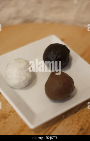 Délicieux blanc, le lait et le chocolat noir boules sur table en bois Banque D'Images