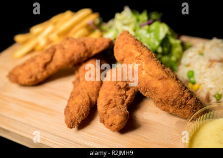 Goujons de poulet servi avec riz, salade et amis français sur bois Banque D'Images