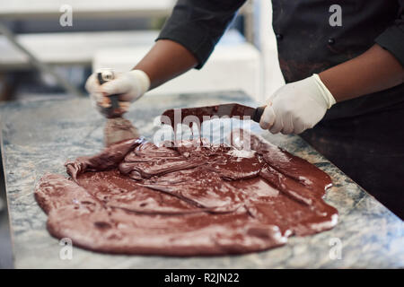 Worker mixing le chocolat sur une table de l'usine de fabrication des produits de confiserie Banque D'Images