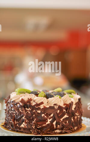 Gâteau aux fruits chocolat avec kiwi, prune et crème fouettée sur le dessus et de morceaux de chocolat autour de Banque D'Images