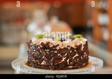 Gâteau aux fruits chocolat avec kiwi, prune et crème fouettée sur le dessus et de morceaux de chocolat autour de Banque D'Images