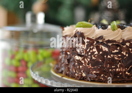 Gâteau aux fruits chocolat avec kiwi, prune et crème fouettée sur le dessus et de morceaux de chocolat autour avec des décorations de Noël Banque D'Images