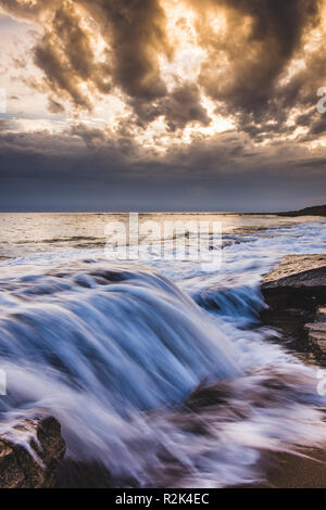 Une longue exposition de vagues se brisant sur les rochers. Banque D'Images