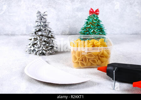 Comment faire un arbre de Noël à partir de pâtes crues conchiglie. Le processus de création d'arbres de Noël à partir de pâtes, des plaques de carton, de la colle à chaud et peinture ou spra Banque D'Images