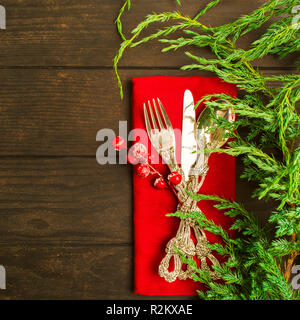 L'argenterie de Noël rouge sur vert sapin avec des tissus sur table en bois Banque D'Images