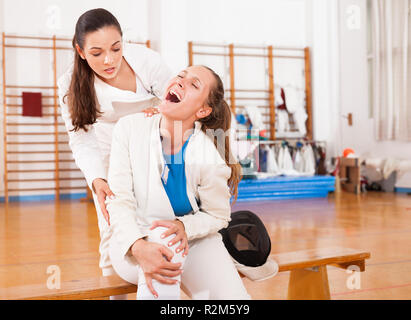 Woman fencer contribuant à une femme qui pleure de douleur après une pratique de mouvements Banque D'Images