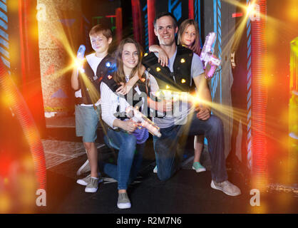 Portrait d'enfants heureux et leurs parents avec des armes à laser poutres couleur laser tag pendant le jeu dans une pièce sombre Banque D'Images