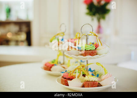 Mini cupcakes au chocolat garnie de mini donuts rose sur une table de dessert. Ils sont affichés sur un écran à plusieurs niveaux.cupcakes avec gastronomique buttercream colorés. Candy bar.focus sélectif.tonique libre Banque D'Images