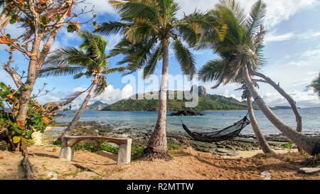 Hamac entre deux palmiers au bord de la mer et vue de Waya Island, Fiji Banque D'Images