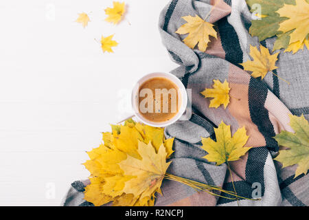Vue supérieure de la grande tasse de café entre télévision disposition des feuilles d'automne et de l'écharpe à damiers sur table en bois blanc, copie de l'espace. Banque D'Images