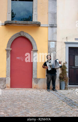 Busker Poruguese jouant accordéon dans la rue pavée Tavira Portugal portugais teint foncé avec des cheveux noirs de l'homme musicien musicien ambulant de la rue barbe mendiant Banque D'Images