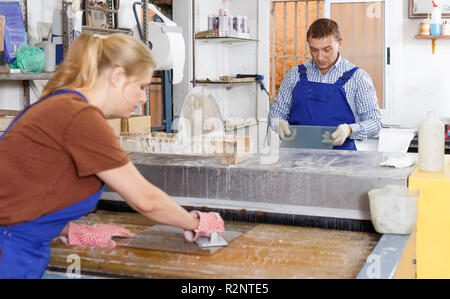 Mâle adulte travailleur avec apprentie travaillant sur verre lave-linge en atelier Banque D'Images