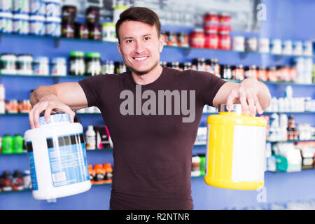 Forme physique guy holding jar en plastique des compléments alimentaires dans le sport d'intérieur boutique Banque D'Images