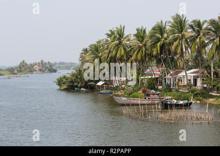 Petit village de pêcheurs sur la rivière bordée de palmiers, à l'extérieur de la ville de Hoi An, Vietnam, photo prise depuis le pont Banque D'Images