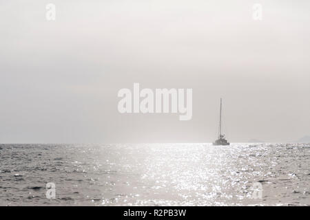 Monochrome, gris, d'une seule image minimaliste, bateau à voile sur la mer ouverte, brillait avec éclat dans le soleil Banque D'Images