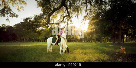 Mother hugging sa fille alors qu'elle est assis sur son cheval. Banque D'Images