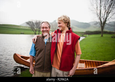 Père et fils debout devant canoe Banque D'Images