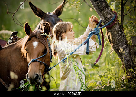 Le partage de adolescente son cheval à un arbre. Banque D'Images