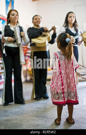 Jeune fille regardant groupe de musiciens jouant de leurs instruments à l'intérieur d'une chambre. Banque D'Images