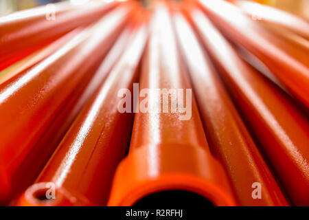 Les tuyaux métalliques recouverts de peinture orange. Arrière-plan avec la perspective. Focus sélectif. Close-up Banque D'Images
