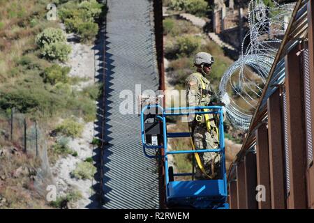 La CPS. Kareem Golbourne, Ingénieur Construction Company, 104e 62e bataillon du génie, des traverses barbelé au sommet de l'Arizona-Mexico mur frontalier, le 7 novembre 2018. Commandement du Nord des États-Unis est fournir du soutien militaire au Ministère de la sécurité intérieure et la U.S. Customs and Border Protection pour sécuriser la frontière sud des États-Unis. (L'Armée Banque D'Images