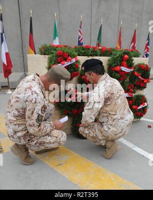 Officiers italiens s'agenouiller devant l'élément central couvert de couronnes de Memorial, de prendre un moment pour montrer du respect à ceux qui ont été perdus au cours de la Première Guerre mondiale, l'épinglage leur revers à la fleur des couronnes à une cérémonie de l'Armistice à l'Union européenne III, à Bagdad le 11 novembre 2018. Le jour de l'Armistice est célébrée chaque année le 11 novembre et coïncide avec le Jour du Souvenir et la Journée des anciens combattants. Tous les jours des anciens combattants rend hommage aux anciens combattants américains, et le Jour du Souvenir rend hommage aux membres des forces armées qui sont morts en servant dans l'exercice de leurs fonctions. Aujourd'hui, la Coalition mondiale pour vaincre l'ISIS a grandi à 74 États membres et cinq organisations internationales Banque D'Images