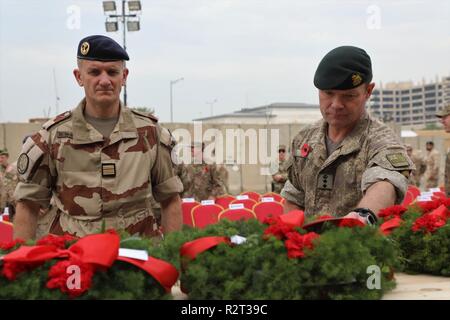 Un officier français et un officier se tient debout devant l'élément central couvert de couronnes de Memorial, de prendre un moment pour montrer du respect à ceux qui ont été perdus au cours de la Première Guerre mondiale, l'épinglage leur revers à la guirlande de fleurs lors d'une cérémonie de l'Armistice à l'Union européenne III, à Bagdad le 11 novembre 2018. Le jour de l'Armistice est célébrée chaque année le 11 novembre et coïncide avec le Jour du Souvenir et la Journée des anciens combattants. Tous les jours des anciens combattants rend hommage aux anciens combattants américains, et le Jour du Souvenir rend hommage aux membres des forces armées qui sont morts en servant dans l'exercice de leurs fonctions. Aujourd'hui, la Coalition mondiale pour vaincre l'ISIS a grandi à 74 états membres Banque D'Images