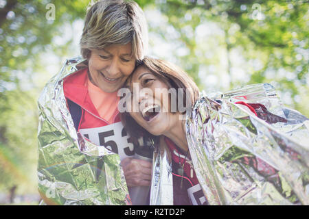 Happy active senior women friends hugging après le sport race, enveloppé dans une couverture thermique Banque D'Images