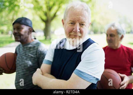 Portrait confiant senior homme jouant au basket-ball avec des amis Banque D'Images