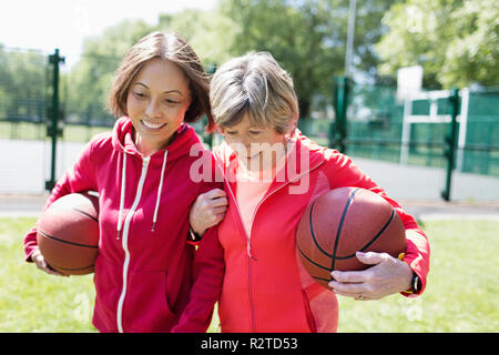 Senior Women friends jouer au basket-ball à sunny park Banque D'Images