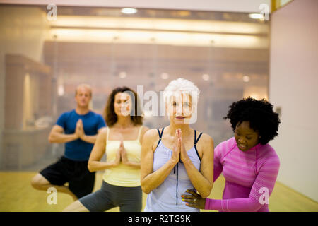 Aider une jeune femme senior woman with her yoga pose à l'intérieur d'un studio. Banque D'Images