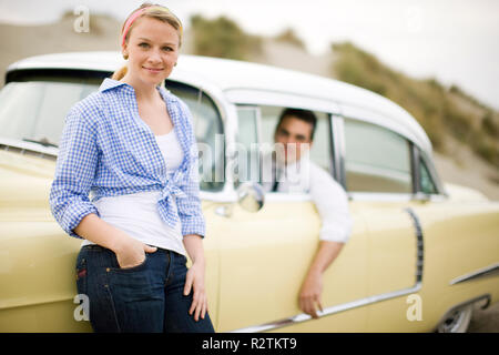 Jeune couple posant avec une voiture ancienne Banque D'Images
