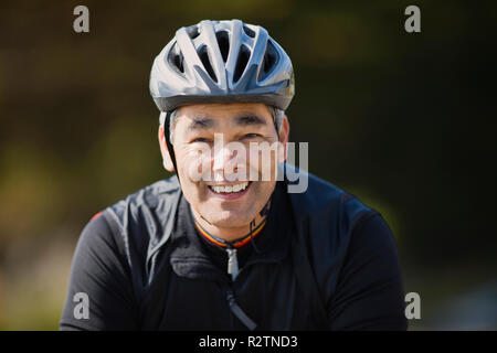 Homme mature portant un casque de vélo et souriant Banque D'Images