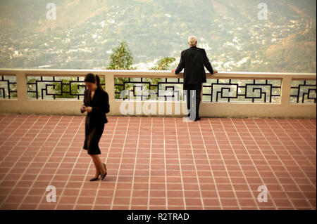 Businessman regarde sur une ville de la vallée d''un balcon comme une collègue s'en va à travers le sol dallé. Banque D'Images