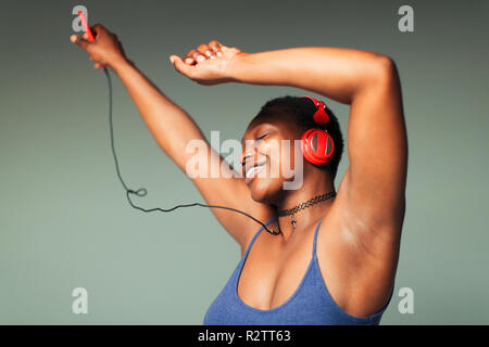 Jeune femme sans souci avec un casque et un lecteur mp3 dancing Banque D'Images