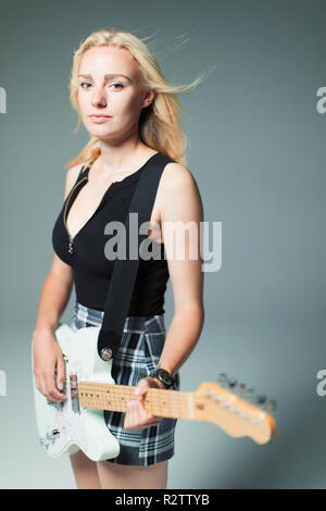 Portrait confiant, cool young woman playing electric guitar Banque D'Images