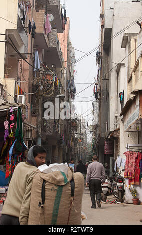 New Delhi, Inde - Le 11 janvier 2015 : rue étroite avec des câbles de suspension et de boutiques panneaux. Les travailleurs. Banque D'Images