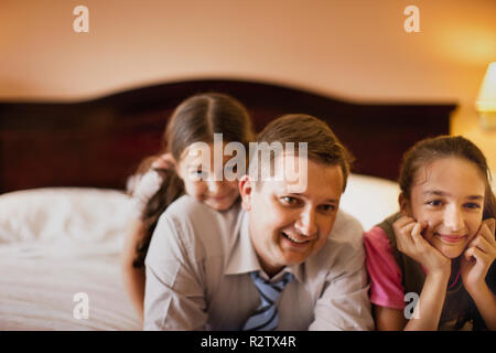 Deux jeunes filles et leur père détente sur lit de l'hôtel. Banque D'Images