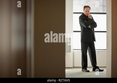 Man in suit se tient à l'extérieur avec les bras croisés. Banque D'Images