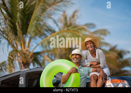 Smiling couple leaning on car avec l'anneau de bain. Banque D'Images
