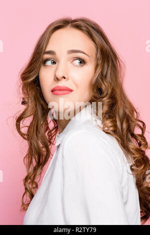 Portrait de jeune femme à la caméra avec arrogance en isolé sur fond de studio rose Banque D'Images