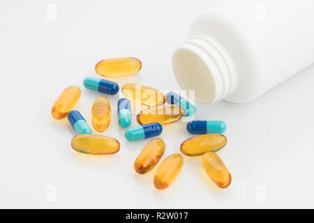 Medical : Close-up of Capsules jaune et bleu avec bouteille et thermomètre analogique sur fond blanc tourné en studio. Banque D'Images