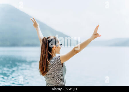 La fille sur le fond de la mer soulève ses mains et montre comment elle est heureuse. Concept de vacances, de la liberté et de l'heure d'été. Banque D'Images