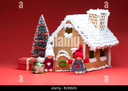 Maison avec des poupées et des biscuits de Noël sur fond rouge Banque D'Images